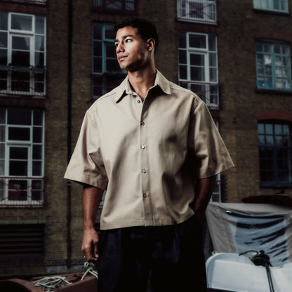 Man standing by a boat in an urban setting with a building in the background